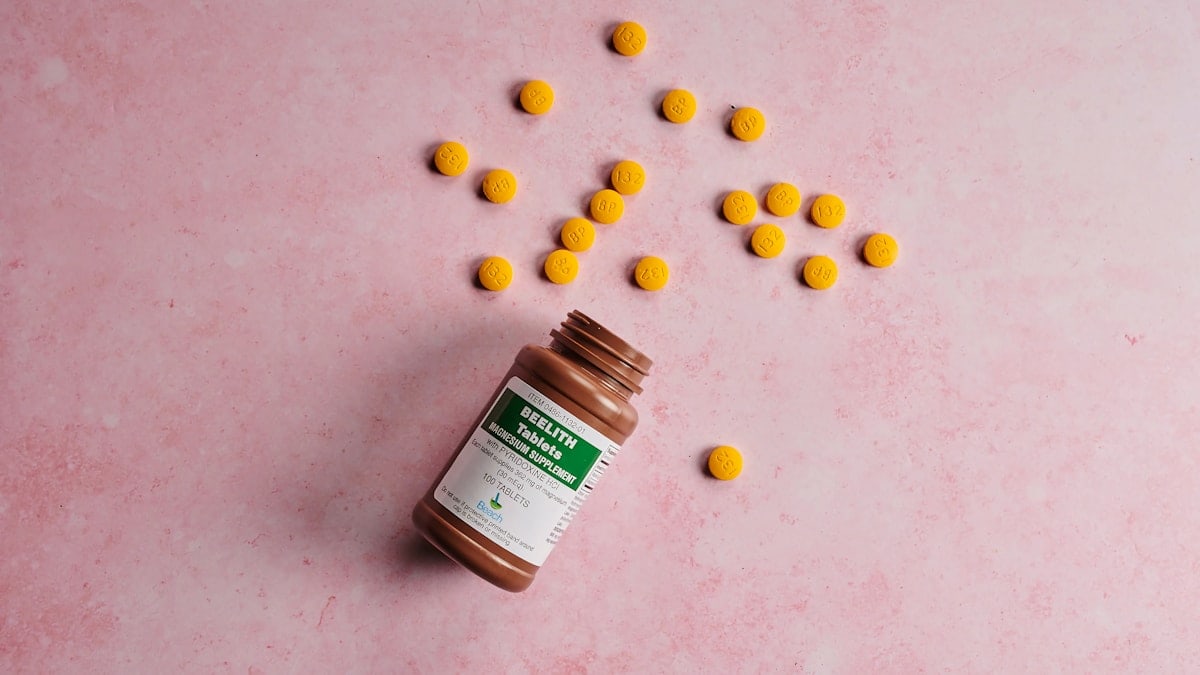 a bottle of medicine with the cap off next to pills
